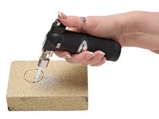 Hand torch mending wire ends together on firing block